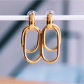 Par de pendientes colgantes dorados de acero inoxidable con diseño de eslabones ovalados entrelazados.