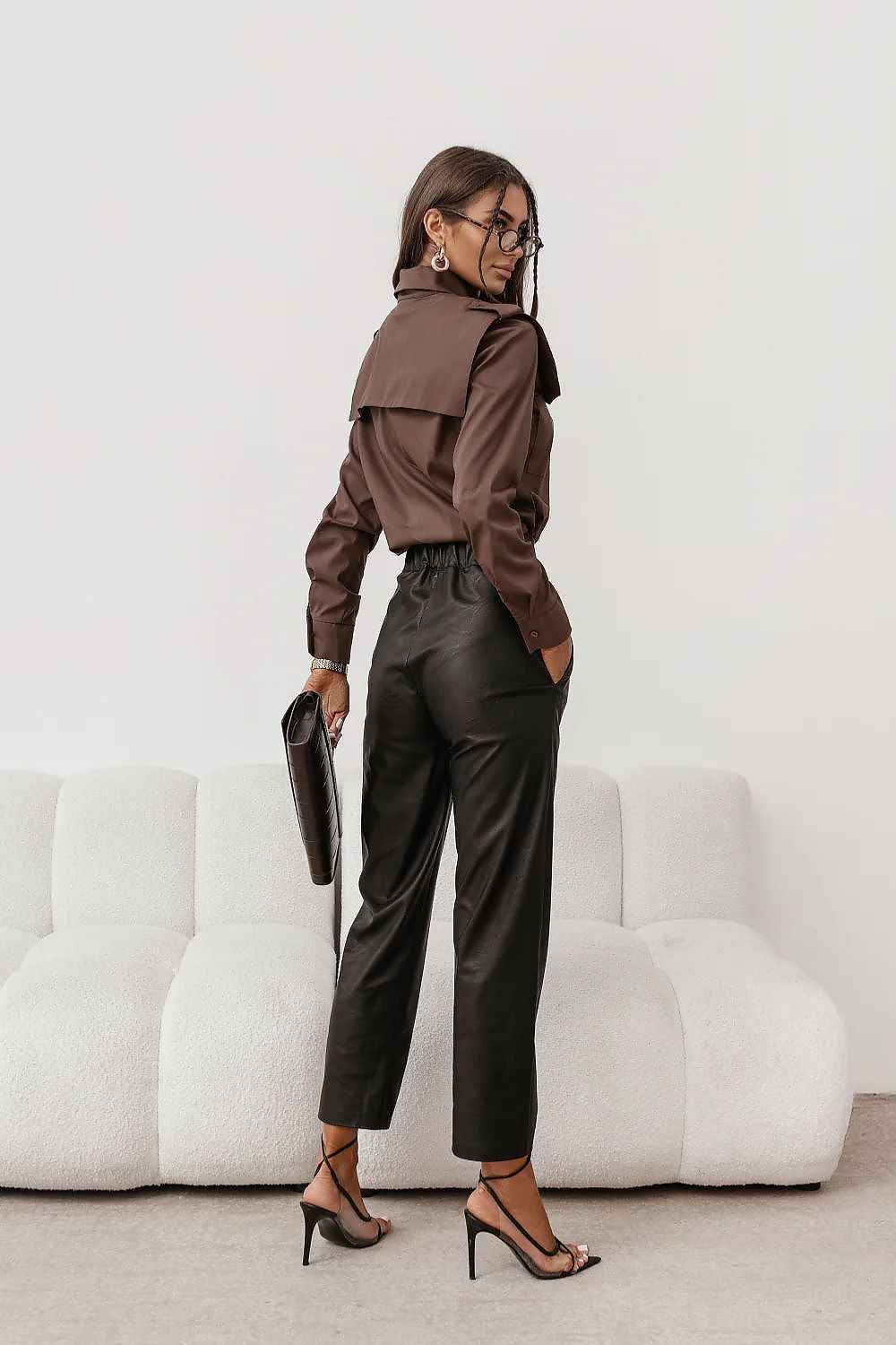 Vista de perfil de una modelo con camisa de diseño color marrón chocolate y lazada al cuello.