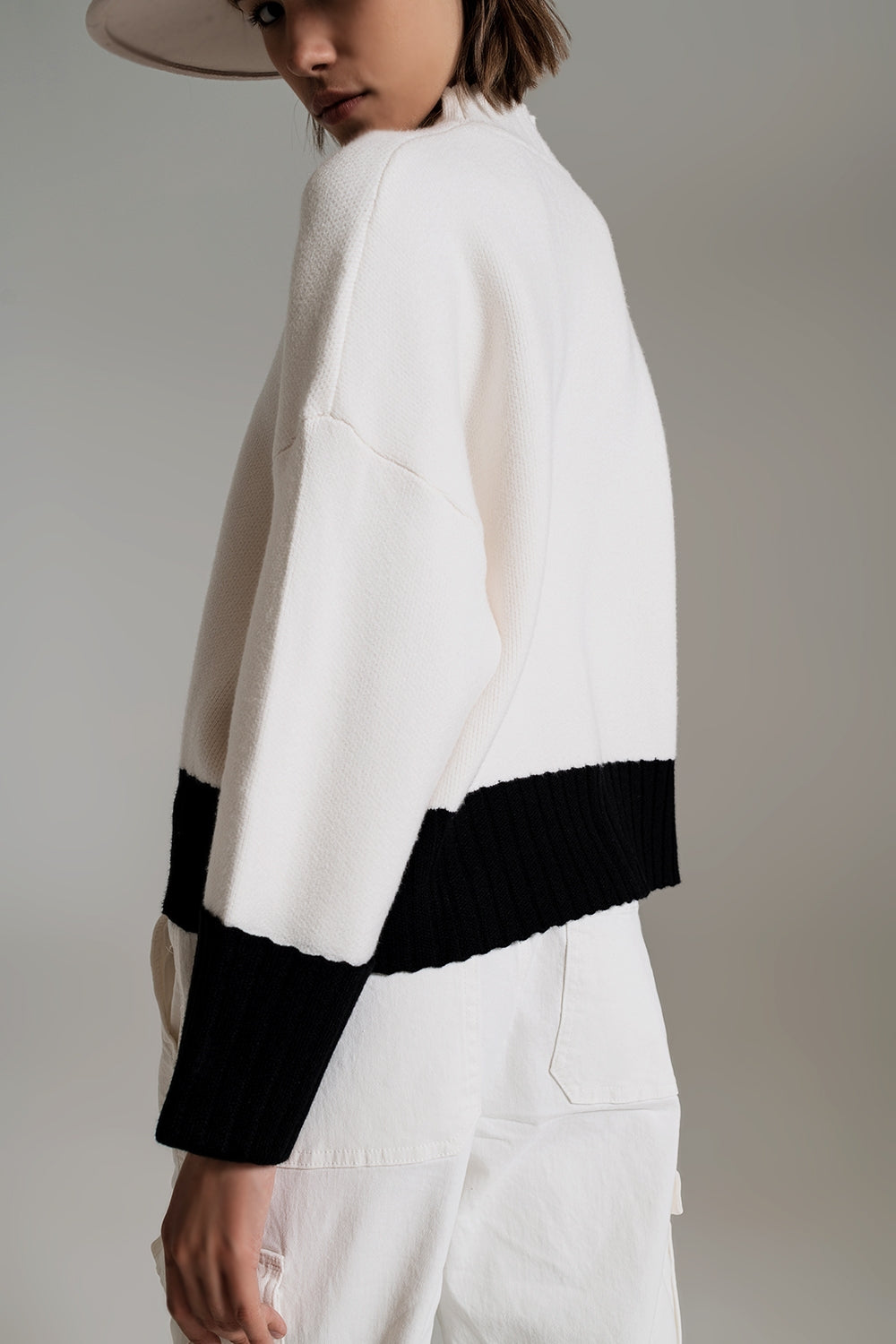 Vista de perfil de un jersey oversize de punto con bajo y puños en color negro.