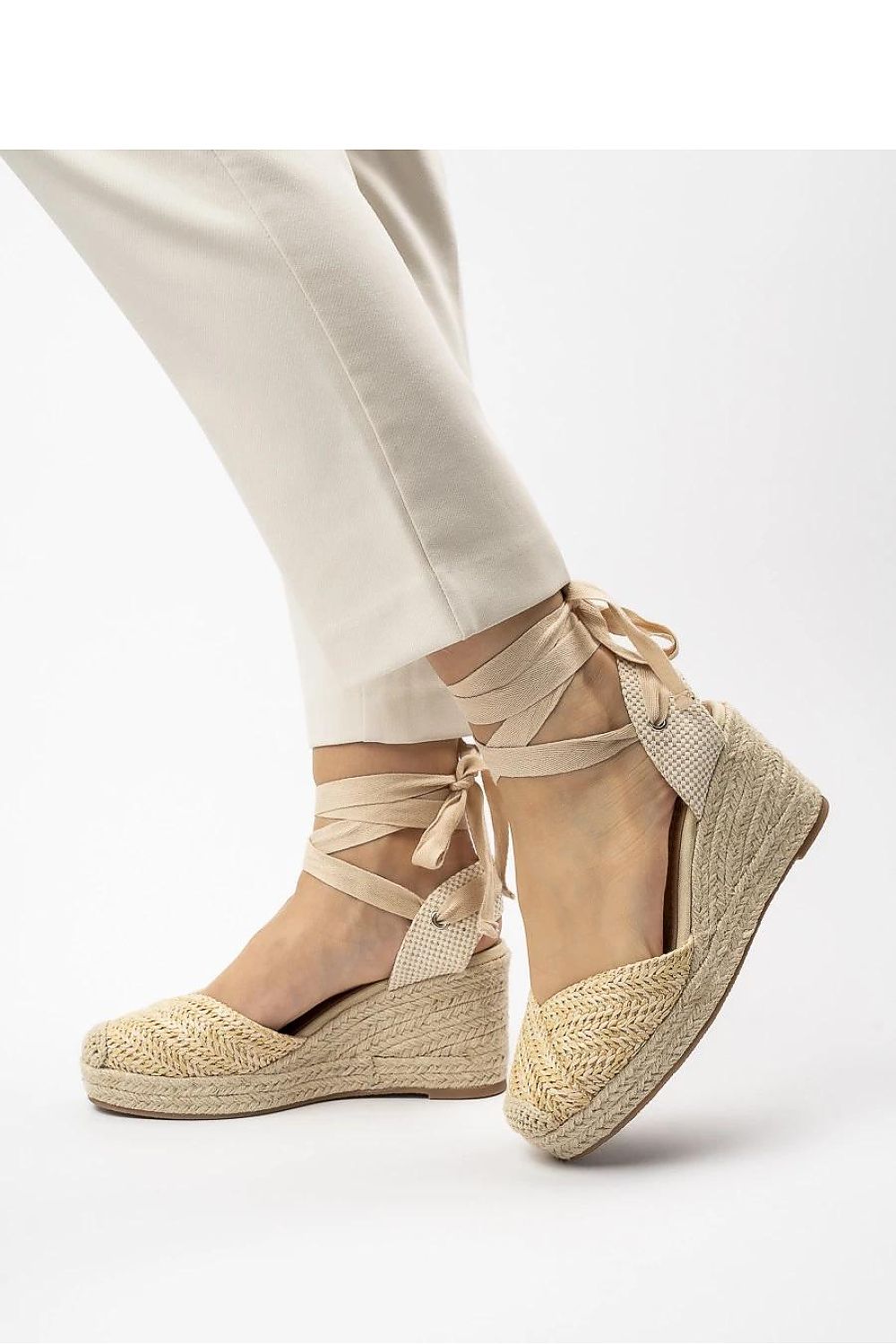  Cuñas beige naturales con lazada al tobillo y pantalón crema.