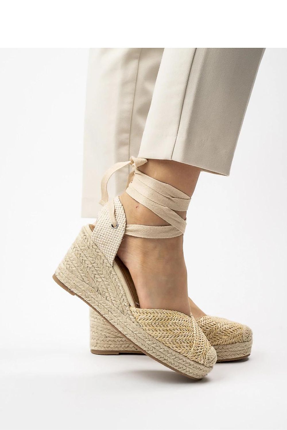  Primer plano lateral de las cuñas beige con cuerda trenzada y lazada.