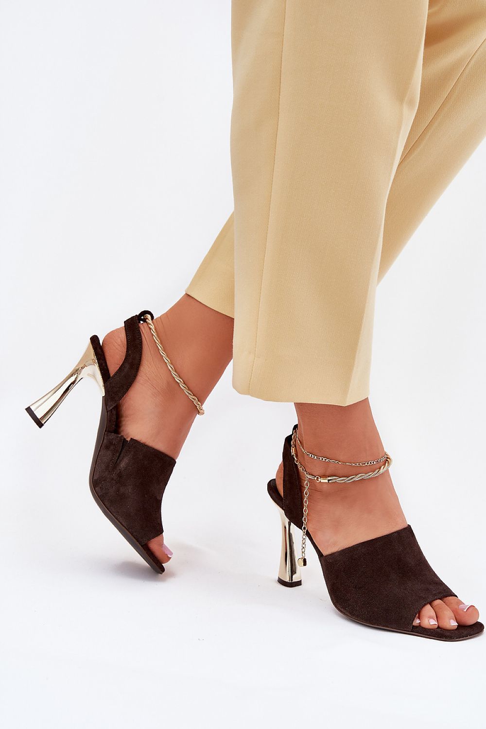 Mujer con sandalias CheBello marrones con tacón dorado.