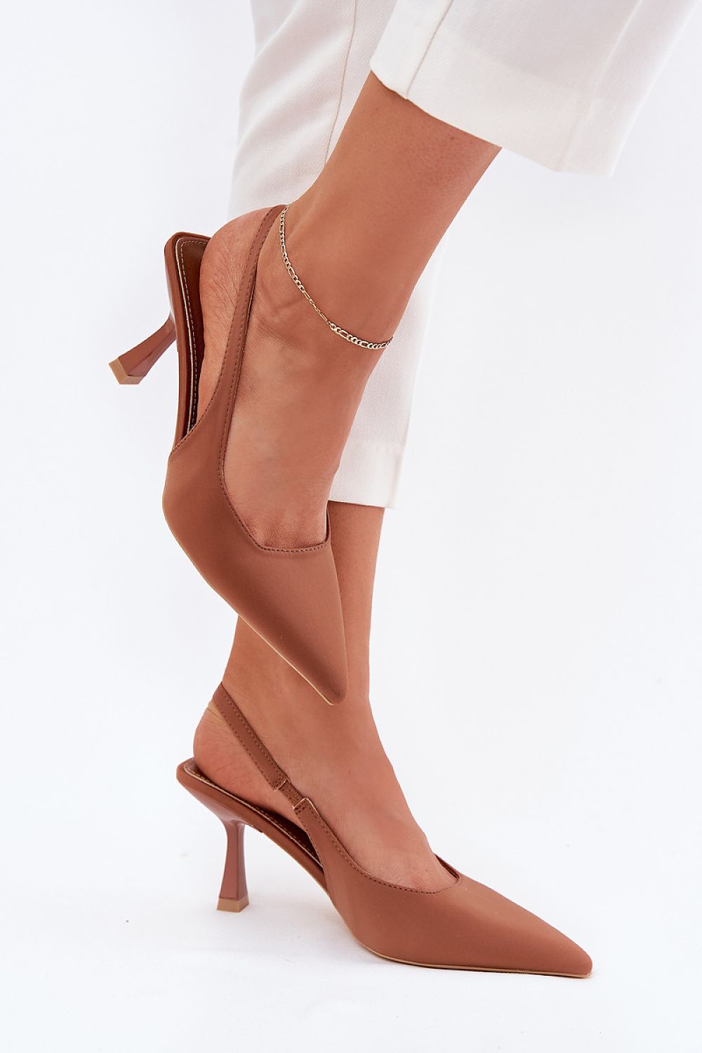 Sandalias marrón chocolate con tacón fino y punta cerrada, combinadas con pantalón claro.