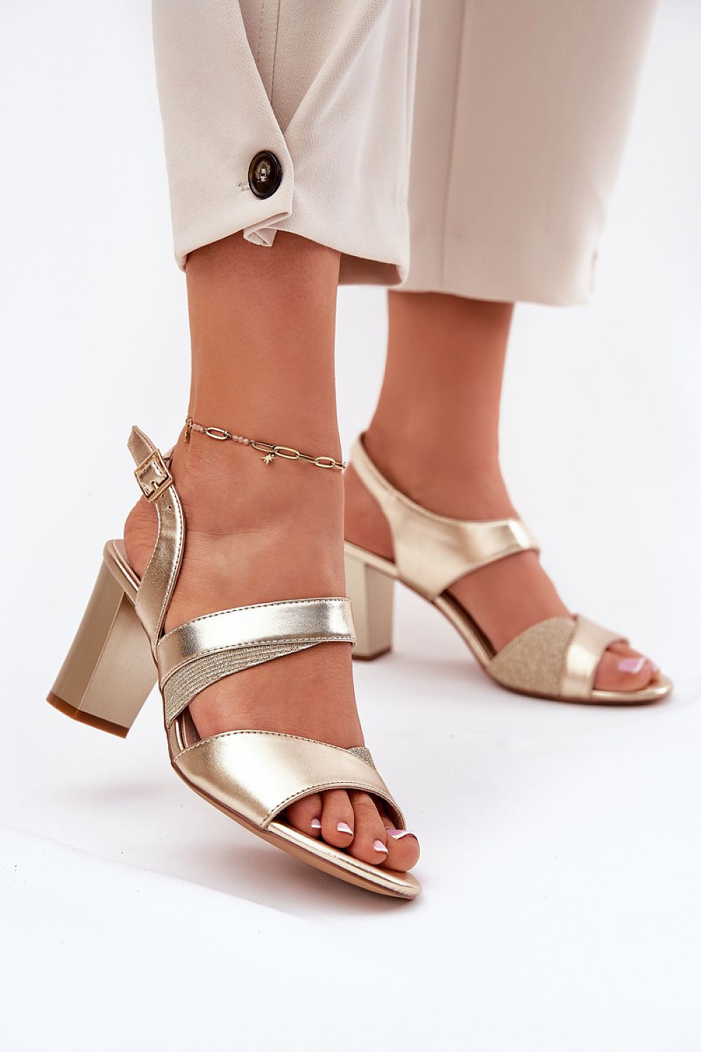 Mujer con sandalias doradas cruzadas de tacón columna