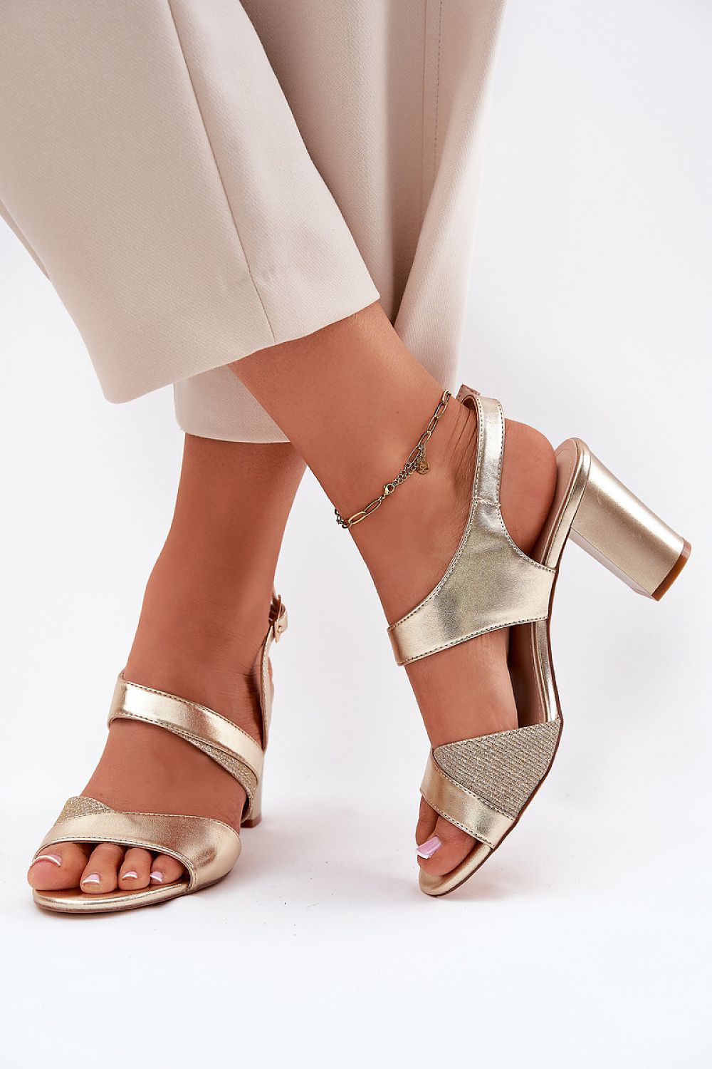 Sandalias doradas con pantalón beige, detalle en primer plano