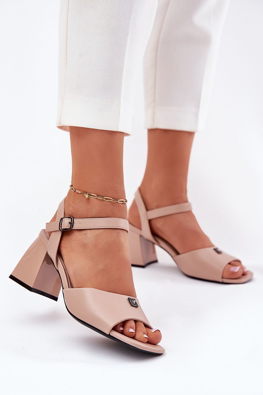 Mujer con sandalias nude de tacón Vinceza, detalle frontal y pantalón blanco