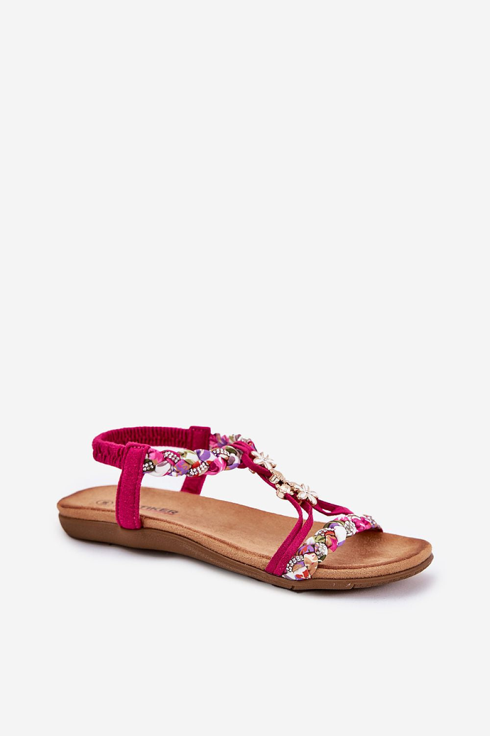 Sandalias fucsia con tiras trenzadas y pedrería floral en fondo blanco.
