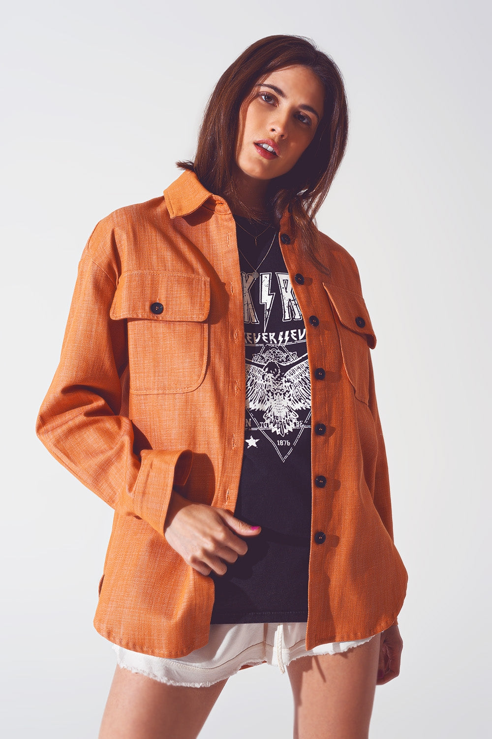 Modelo vistiendo sobrecamisa naranja de algodón 100% con bolsillos en el pecho y corte amplio.