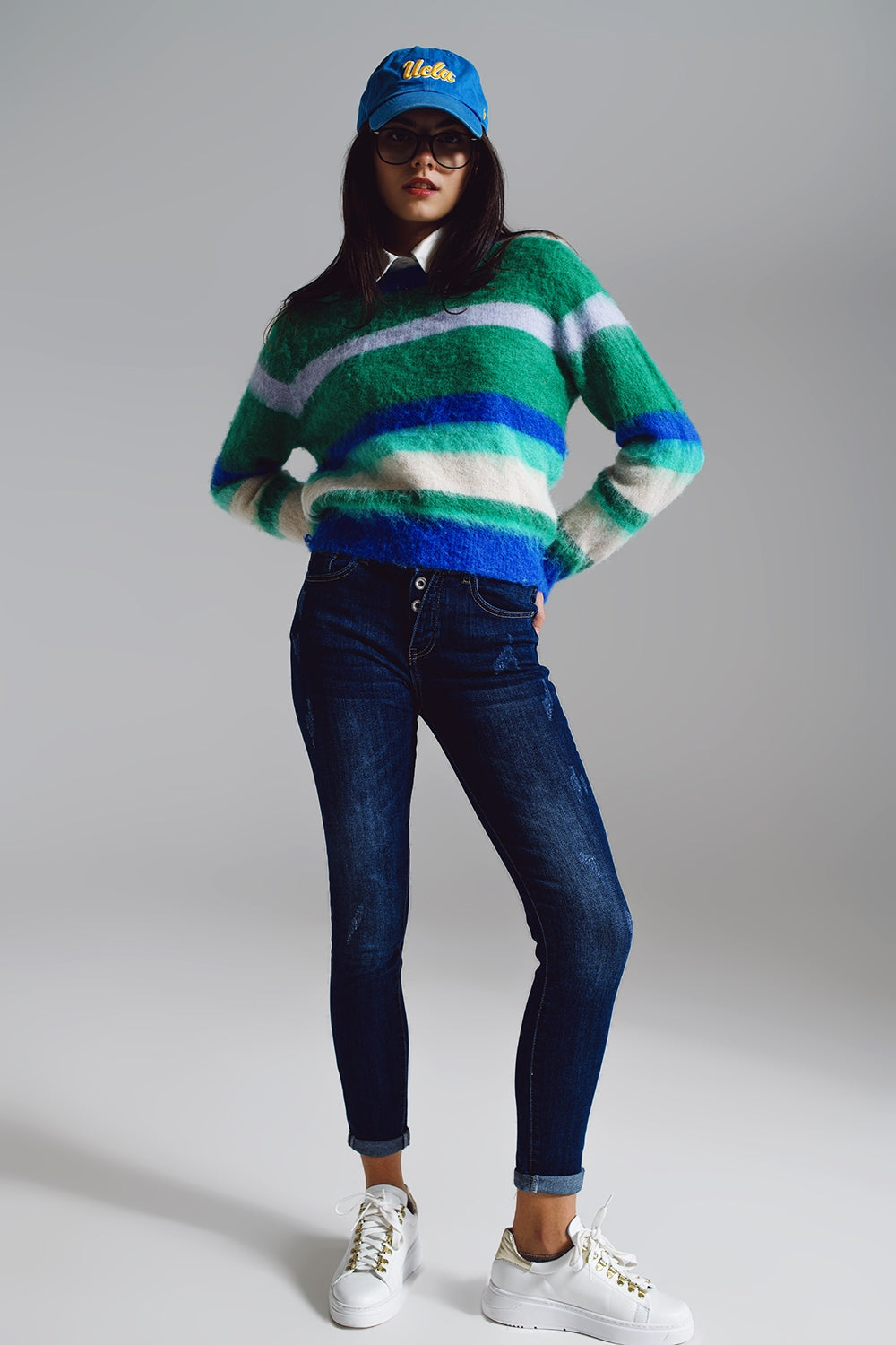 Modelo con look completo de jersey de punto suave a rayas y vaqueros oscuros.