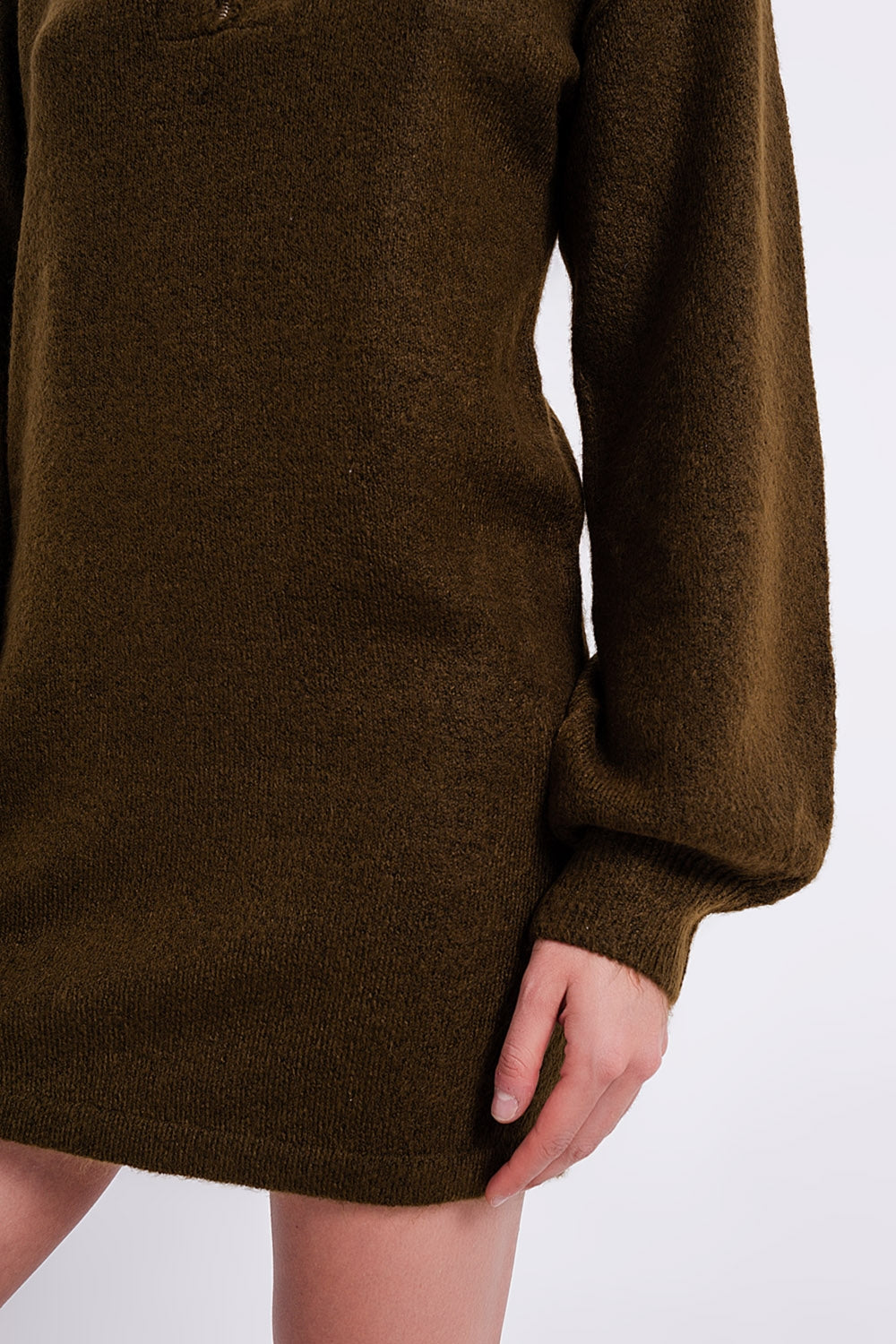 Detalle lateral de la textura del tejido de punto acrílico verde y el puño de la manga.