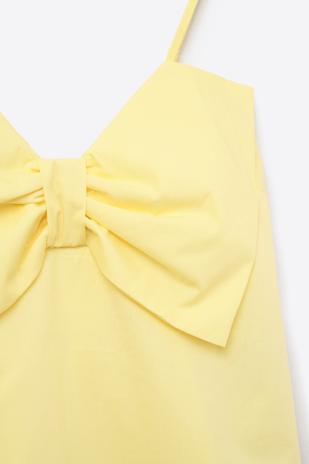 Top de tirantes en color amarillo mantequilla confeccionado en popelina con un gran lazo estructurado en el pecho.