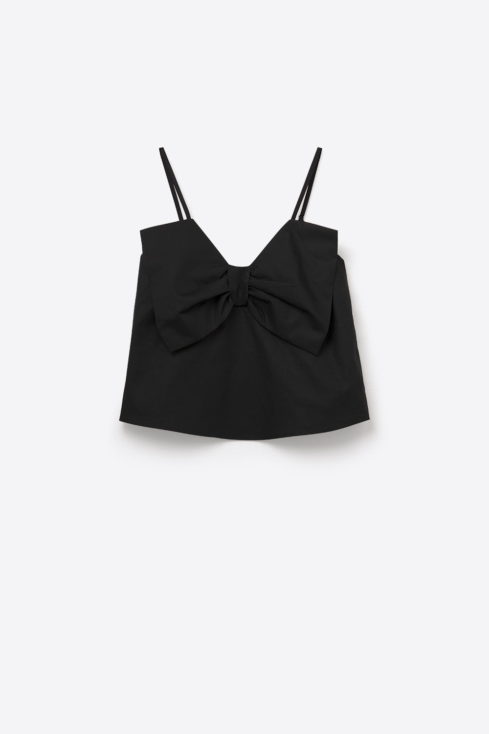 Top negro de tirantes con un gran lazo estructurado en el pecho, combinado con pantalones blancos de vestir.