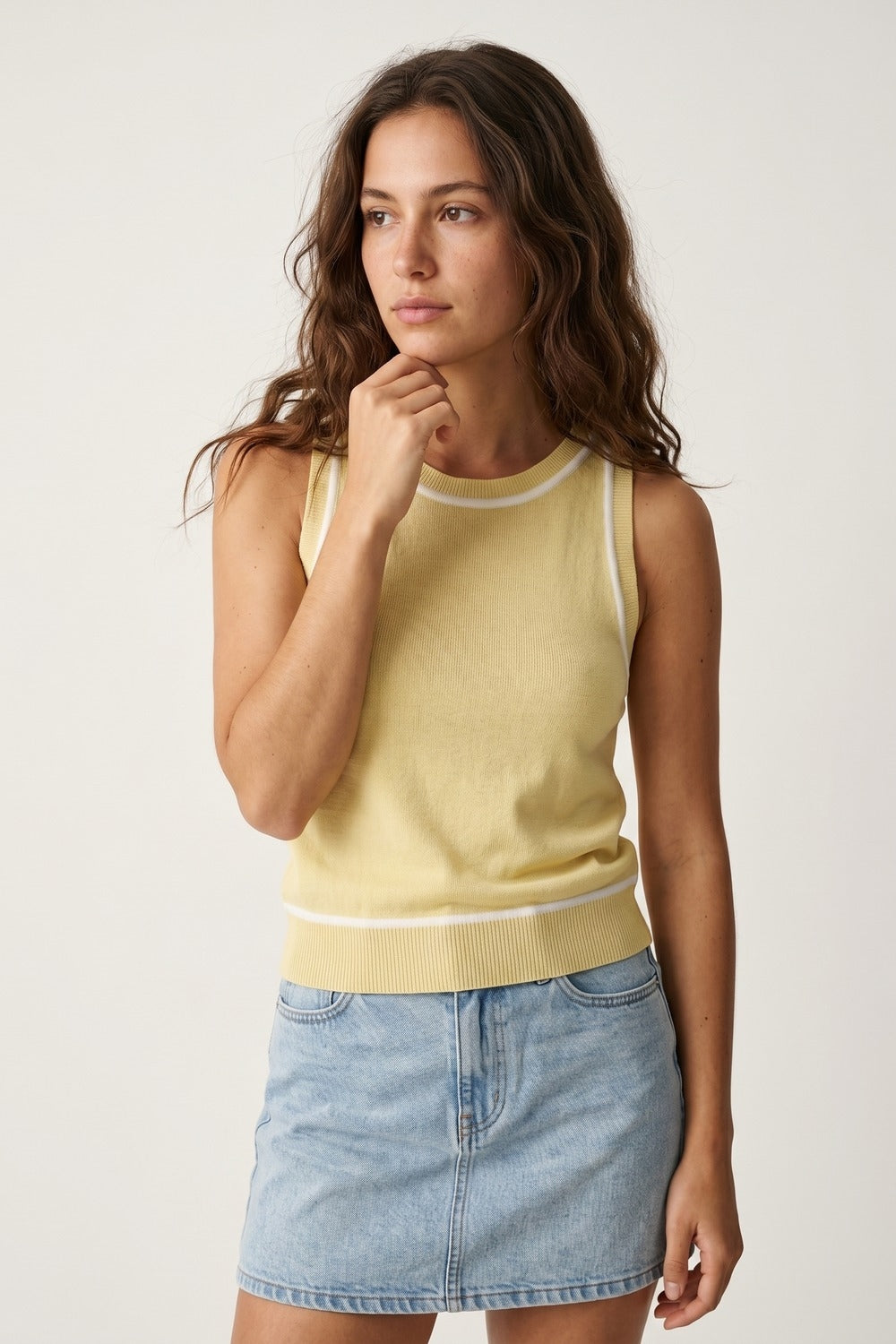Top halter amarillo mantequilla de punto fino con ribetes blancos combinado con falda vaquera clara.