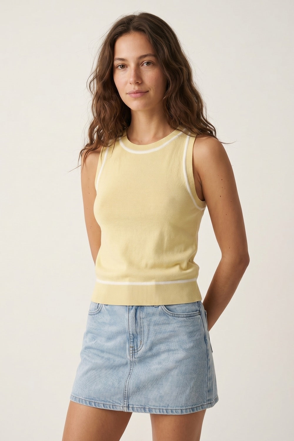 Top halter amarillo mantequilla de punto fino con ribetes blancos combinado con falda vaquera clara.