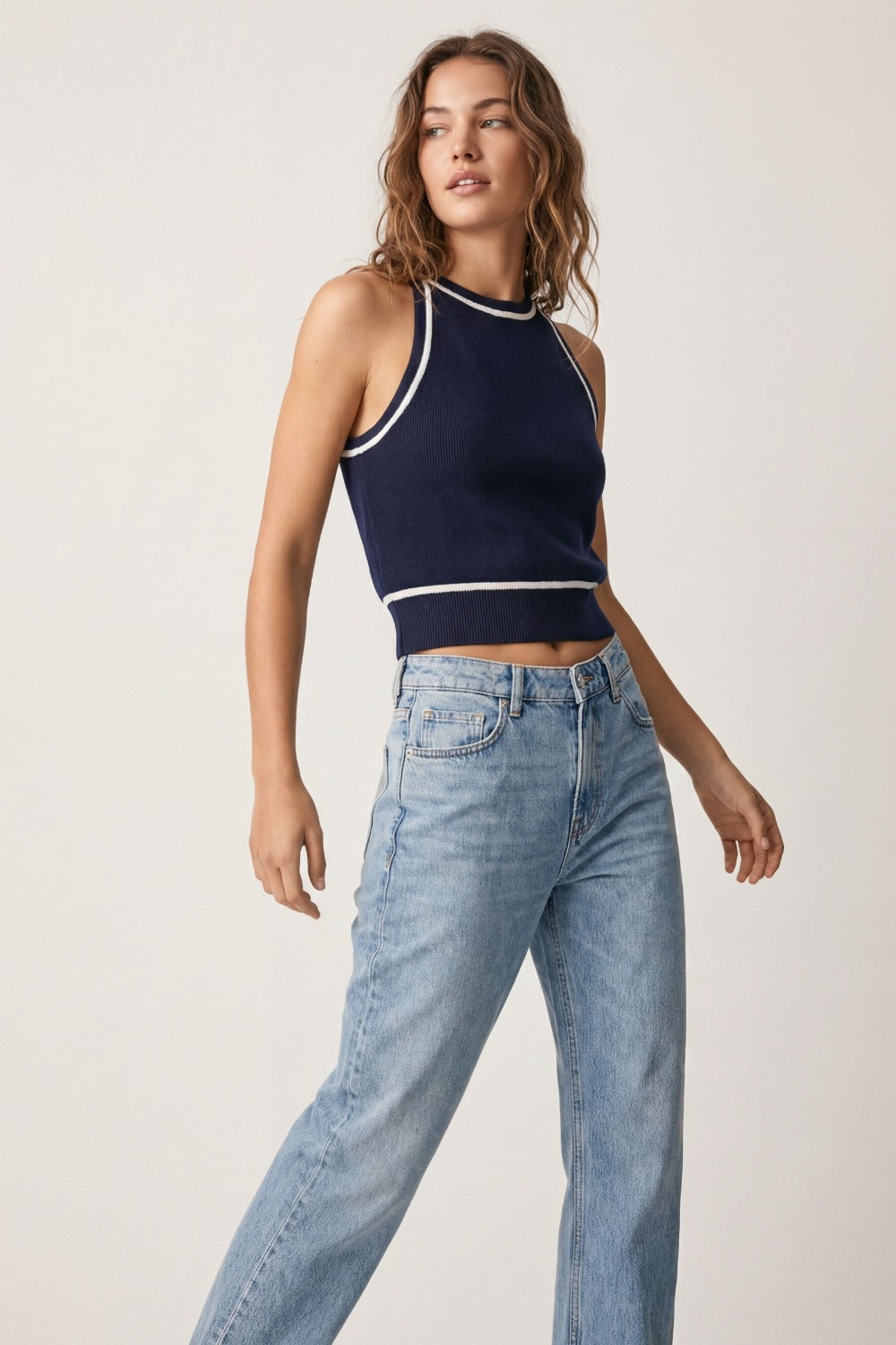 Top halter azul marino de punto fino con detalles blancos combinado con vaqueros claros de tiro alto.
