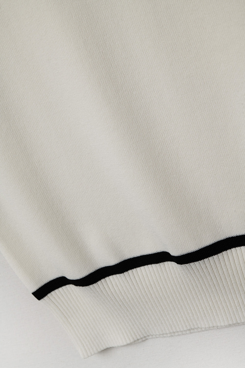 Top halter blanco de punto fino con detalles negros en contraste y corte ajustado.