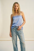 top lencero azul claro con encaje floral y vaqueros denim claros.