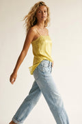 top de raso amarillo con encaje floral y tirantes finos combinado con vaqueros claros.