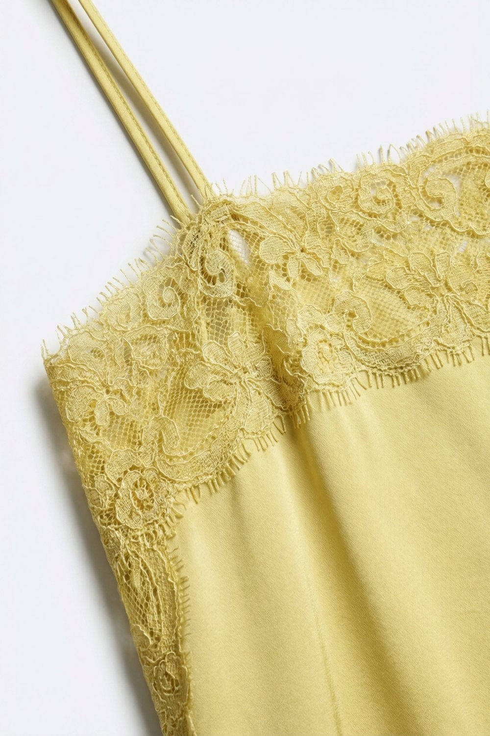 Detalle top de raso amarillo con encaje floral y tirantes finos