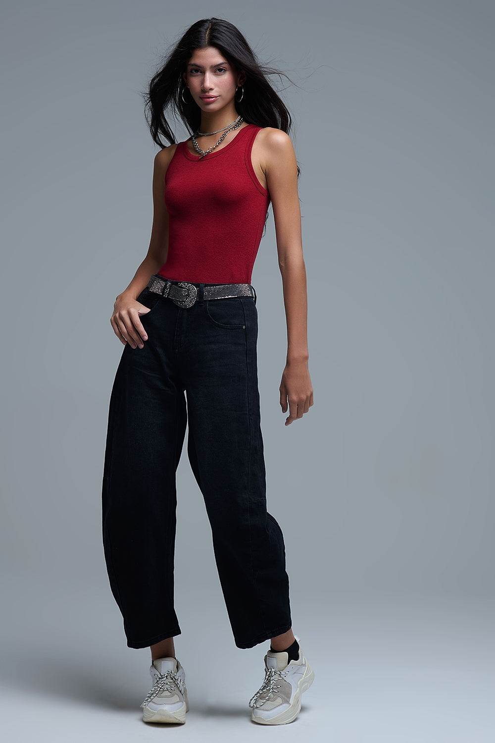 Look completo de mujer con top rojo de punto ajustado, vaqueros baggy negros y zapatillas chunky.