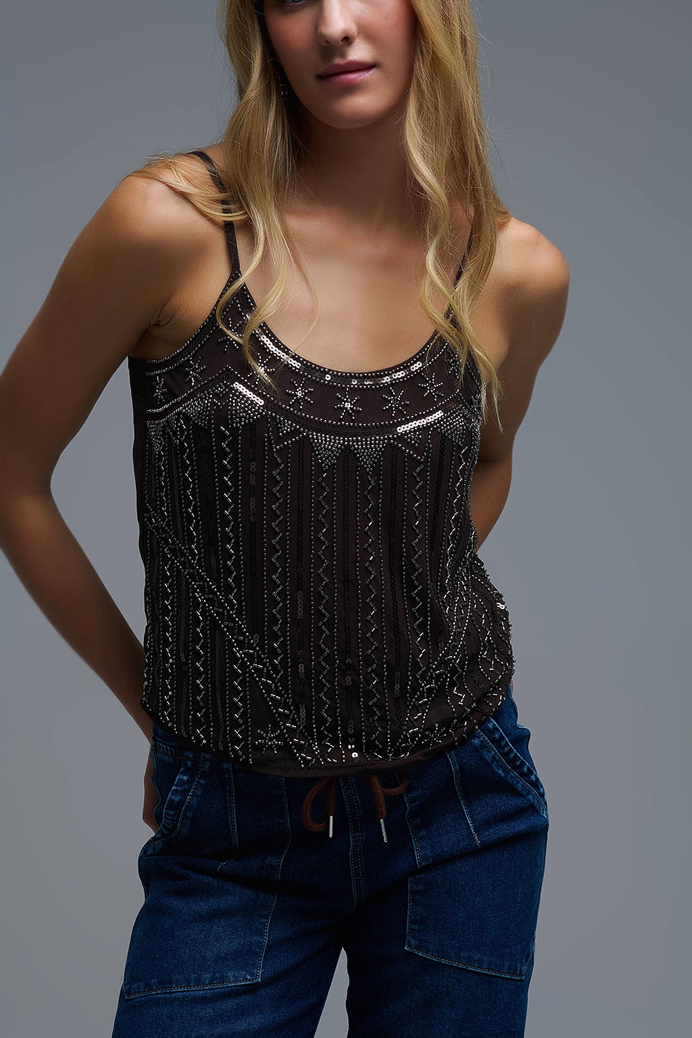 Plano medio de mujer vistiendo camisola marrón estilo vintage con decoración de pedrería y lentejuelas.