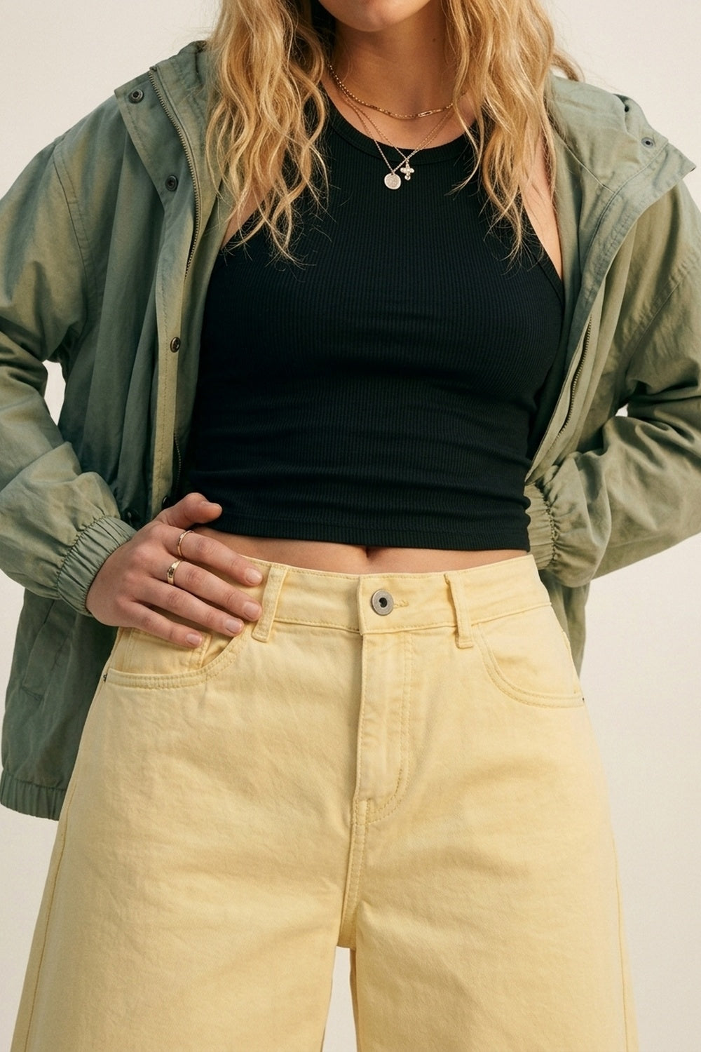 Bermudas vaqueras tipo culotte en color amarillo pastel de tiro alto, combinadas con top cropped negro y zapatillas deportivas envejecidas.