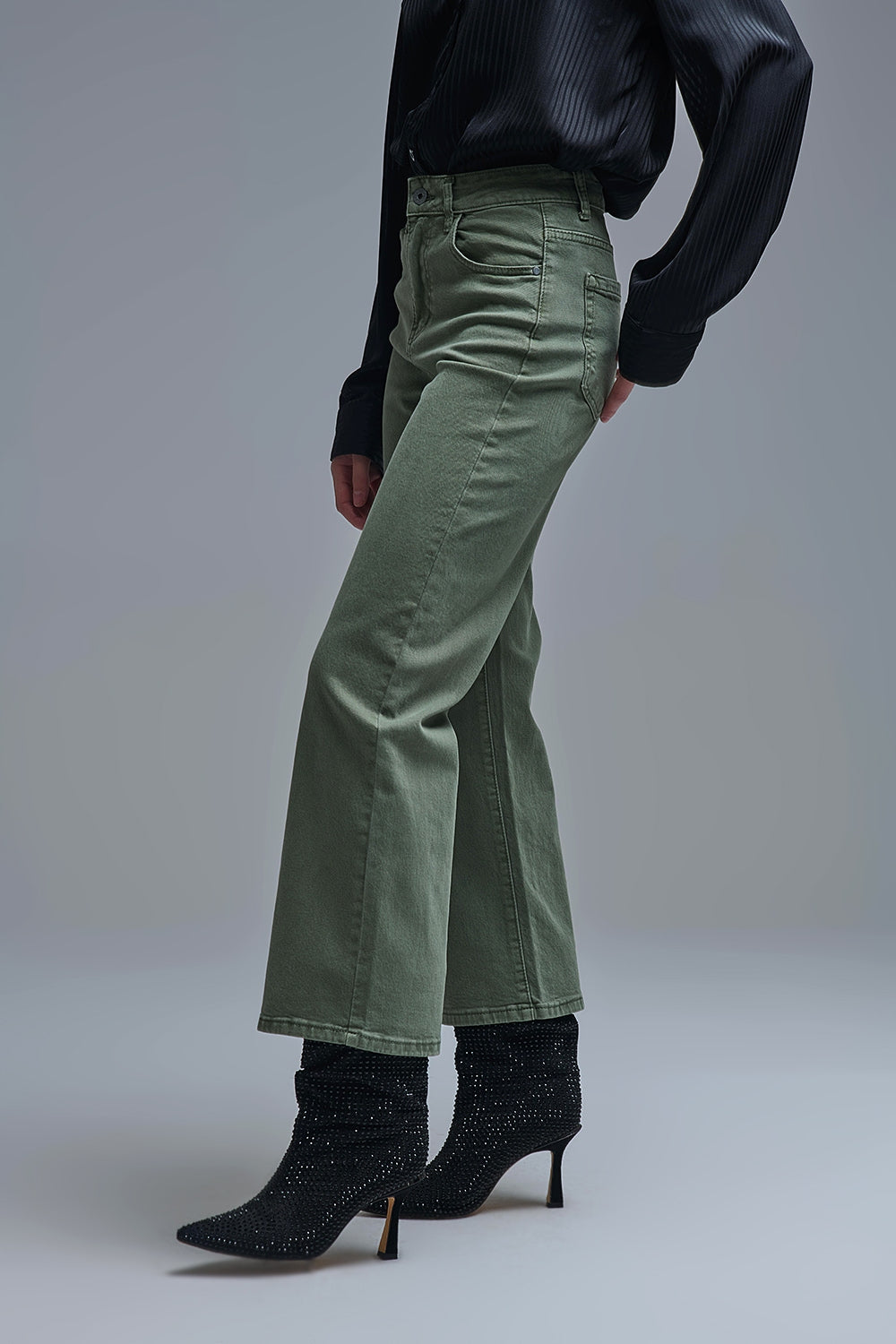Vaquero de mujer de pierna ancha en color verde caqui, largo al tobillo, combinado con botines negros y blusa oscura.