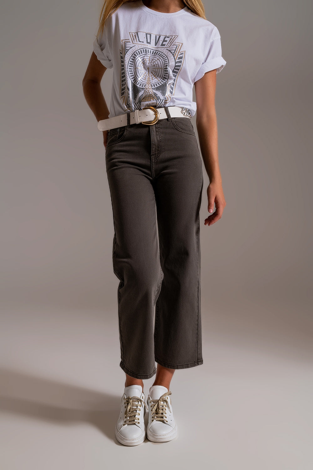 Mujer vistiendo vaqueros culotte de color gris humo con camiseta blanca gráfica y cinturón blanco.