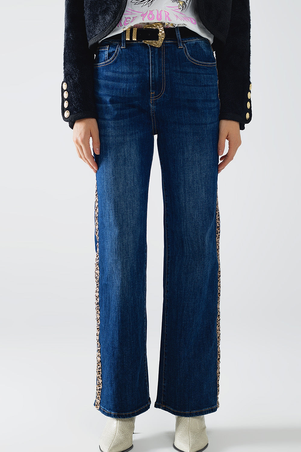 Modelo con vaquero de pernera ancha y lavado oscuro con una raya lateral de estampado de leopardo.