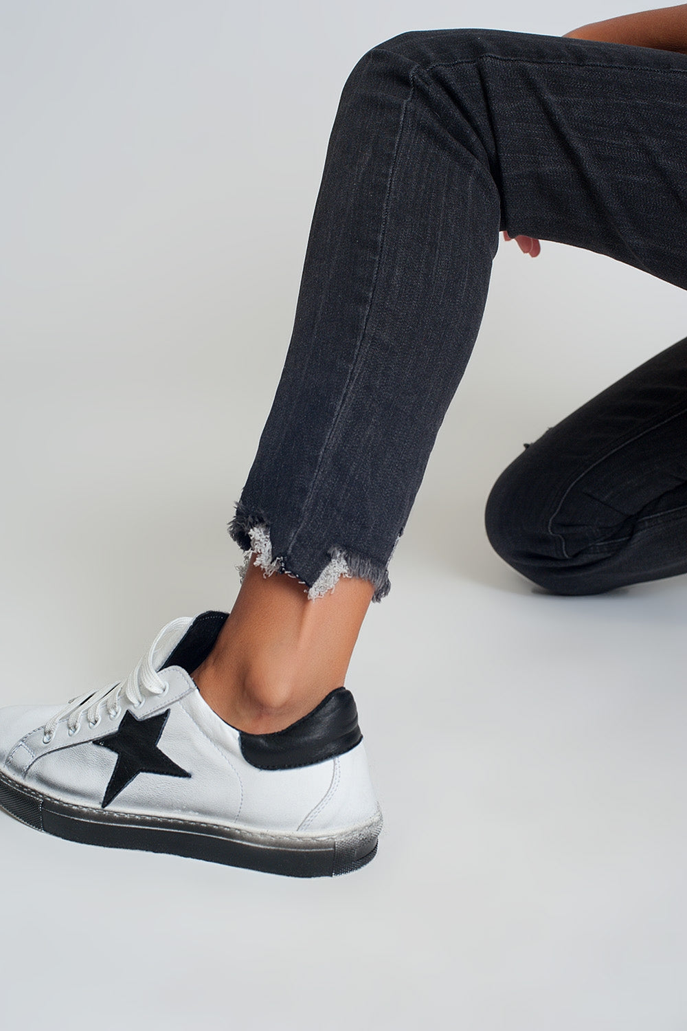 Vaqueros de talle medio en negro con bajo sin rematar