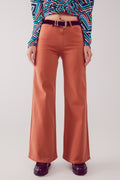 Modelo con pantalón acampanado de talle alto en color naranja teja y top estampado