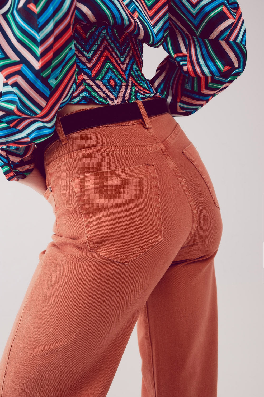 Vista trasera de un pantalón acampanado de algodón en color naranja teja.