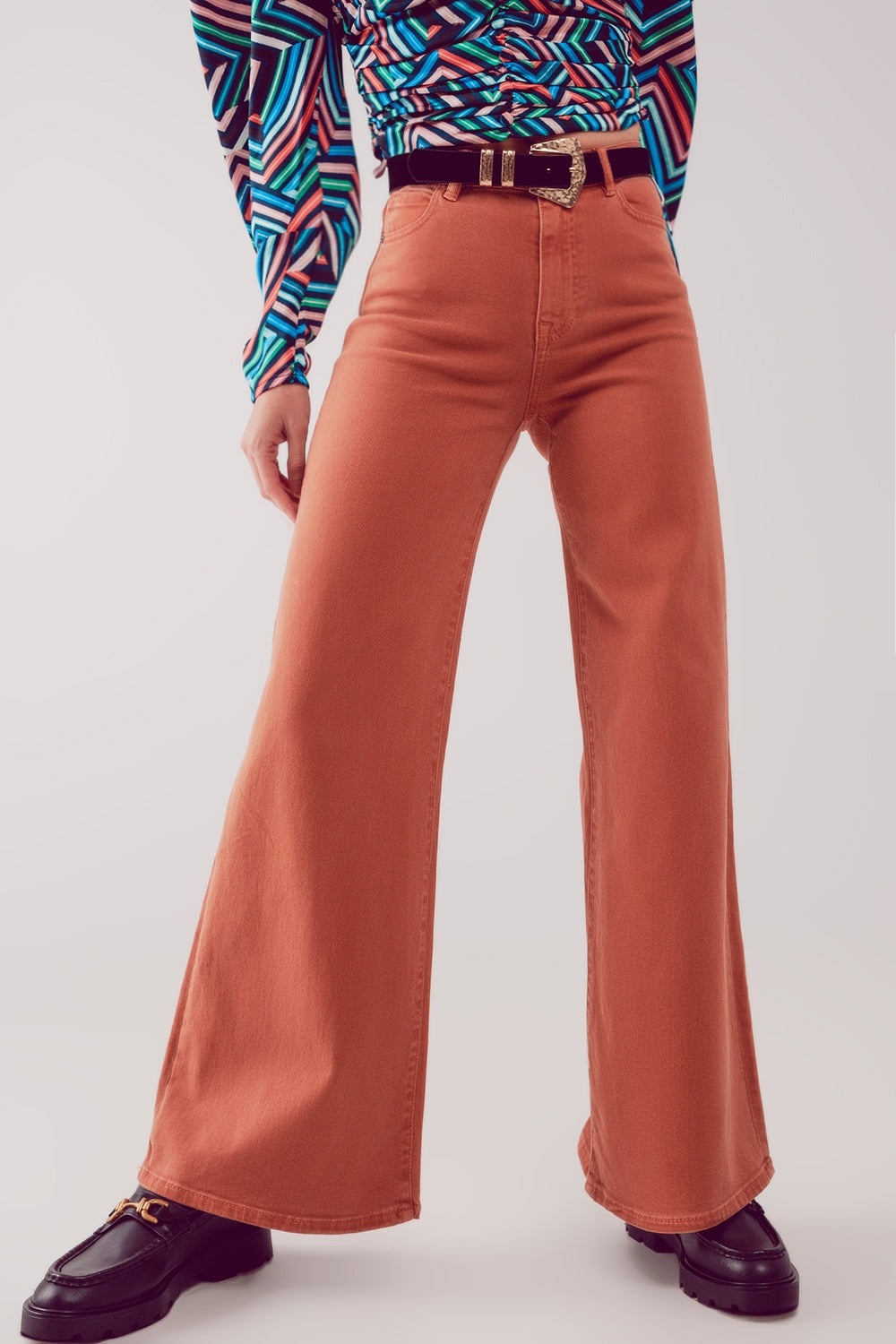 Modelo con pantalón acampanado de talle alto en color naranja teja 