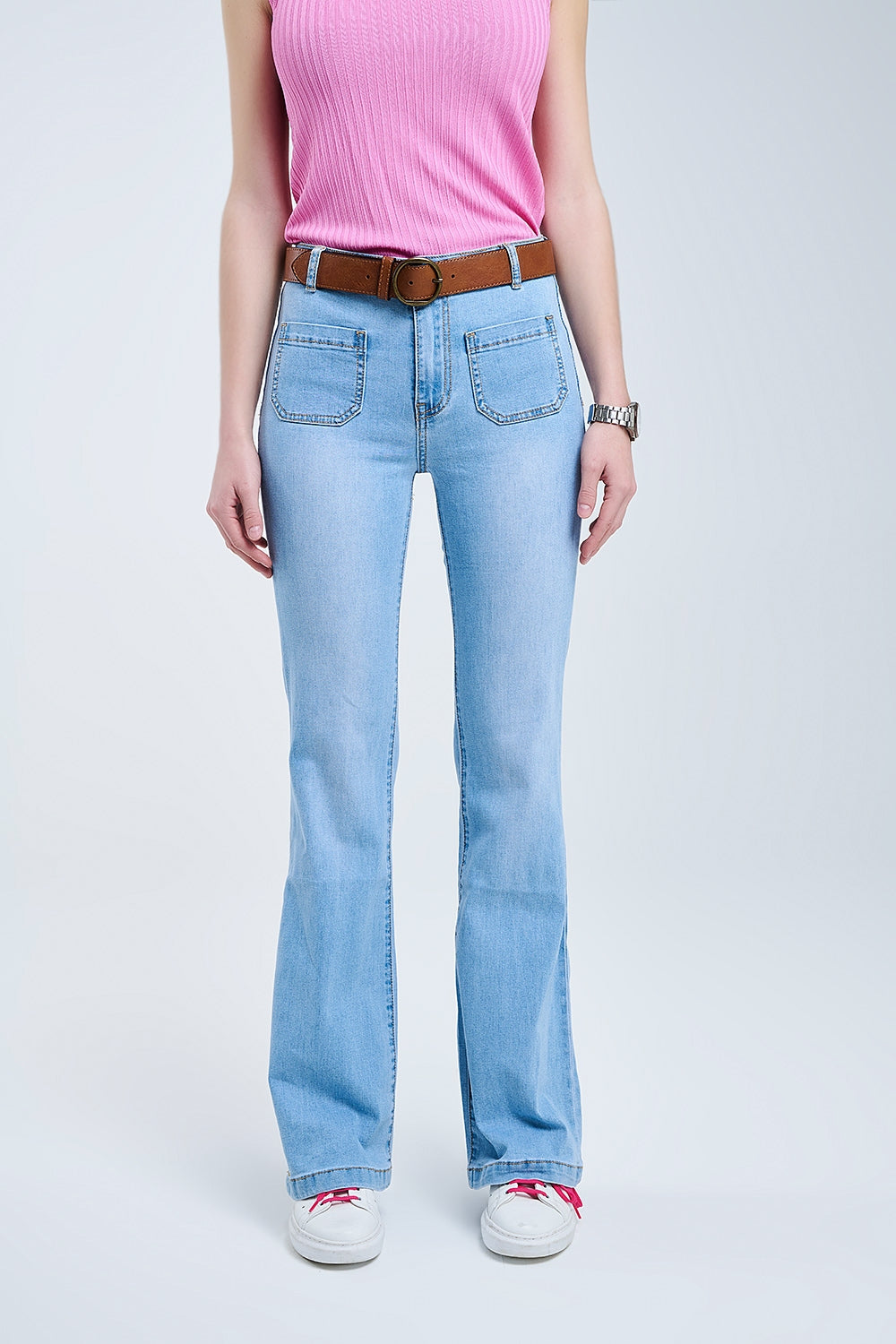 Modelo con vaquero de corte bootcut y tiro alto en lavado azul claro, con bolsillos de parche frontales.