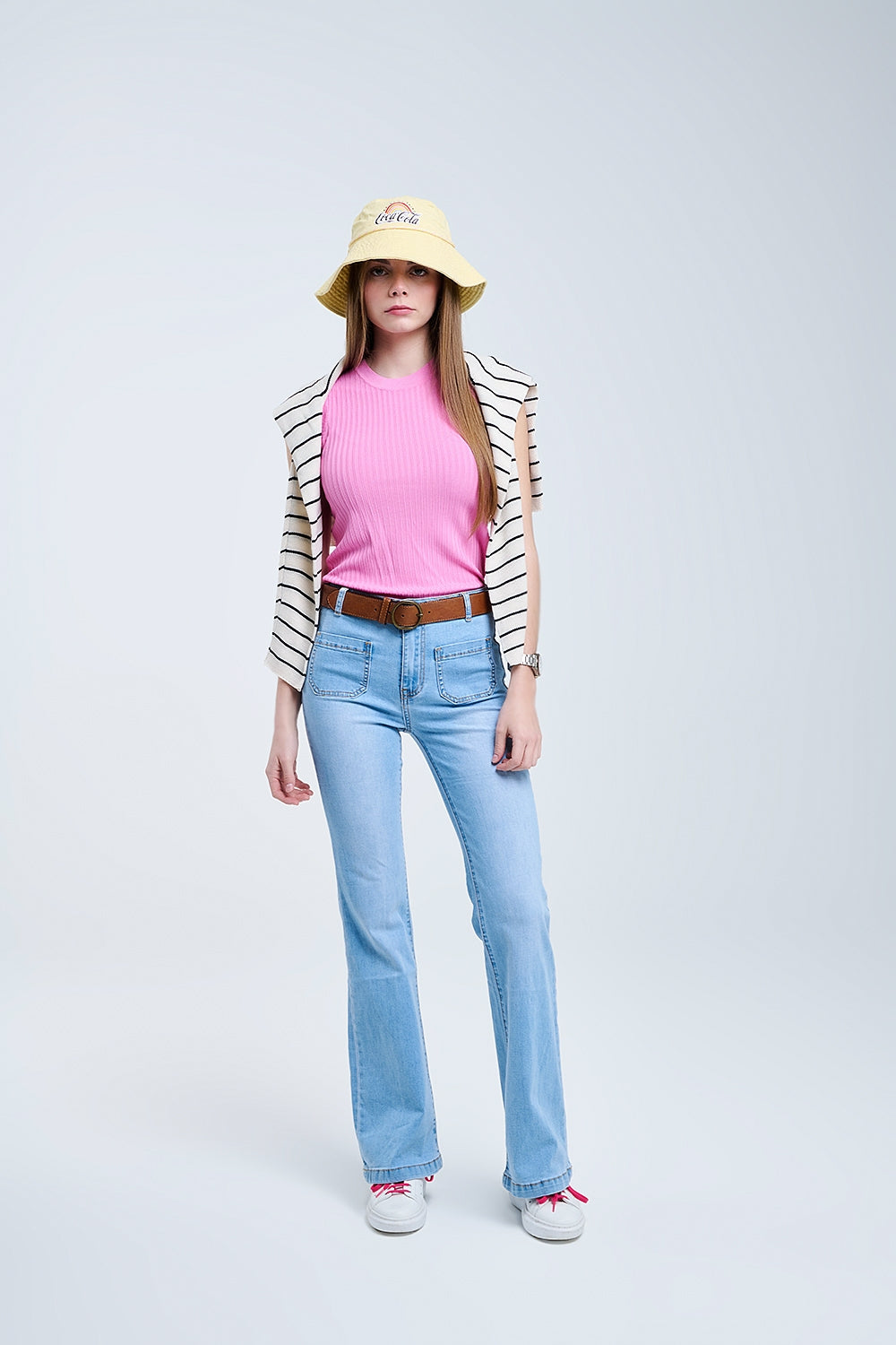 Modelo con vaquero de corte bootcut y tiro alto en lavado azul claro, con bolsillos de parche frontales.