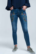vaqueros pitillo azules con bordados de flores en los muslos y bajo deshilachado estilo boho.