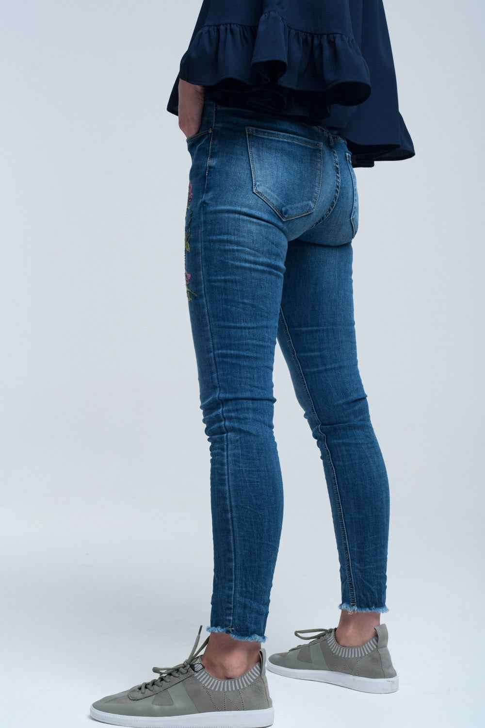 vaqueros pitillo azules con bordados de flores en los muslos y bajo deshilachado estilo boho.