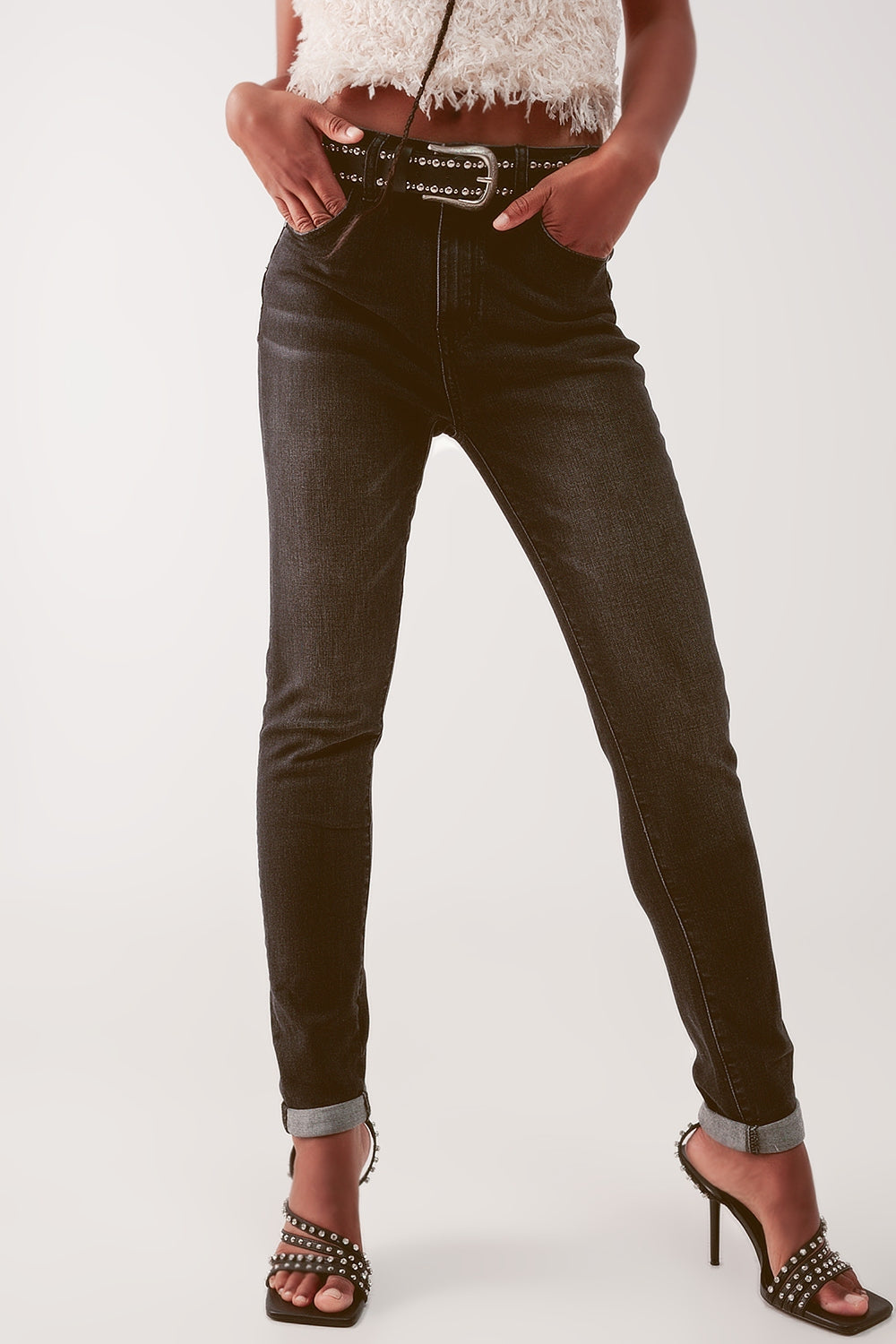 Modelo con vaquero pitillo de talle alto en color negro desgastado, combinado con un top de fiesta y tacones.