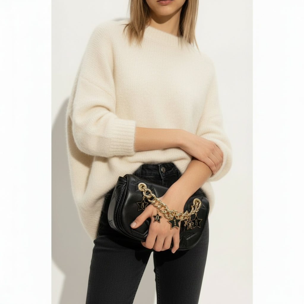 Vista frontal de bolso negro acolchado con estrellas y cadena dorada con letras colgantes de la marca Versace.