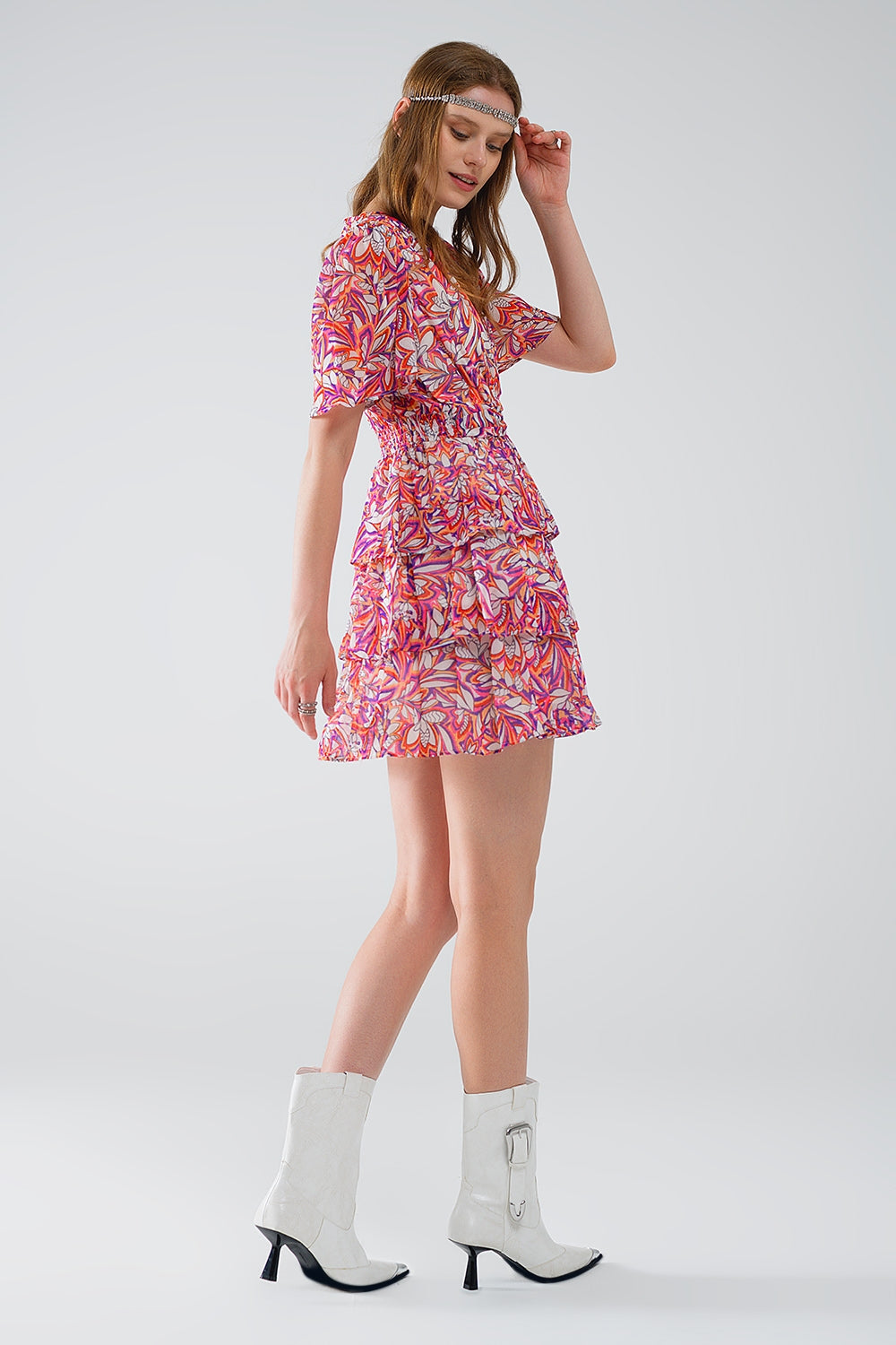 Mujer vistiendo vestido corto de gasa con estampado floral vibrante, volantes y botines blancos.