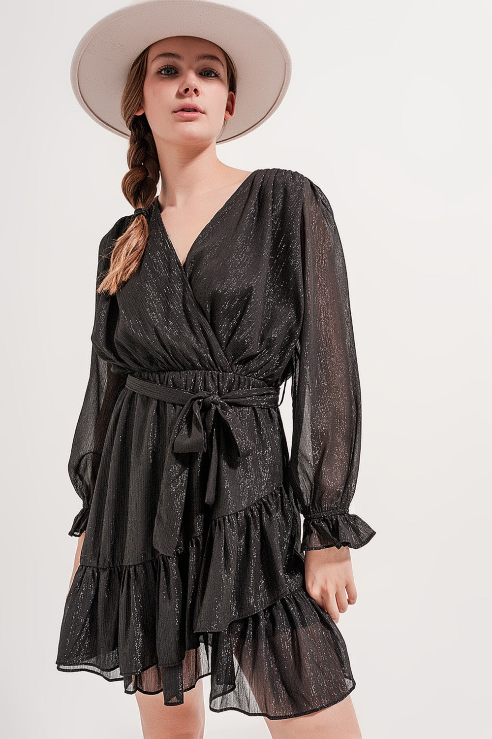 Primer plano de un vestido negro cruzado mostrando la textura del tejido con hilo metalizado.