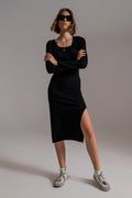 Modelo con vestido midi de punto ajustado en color negro, de manga larga y con escote cuadrado.