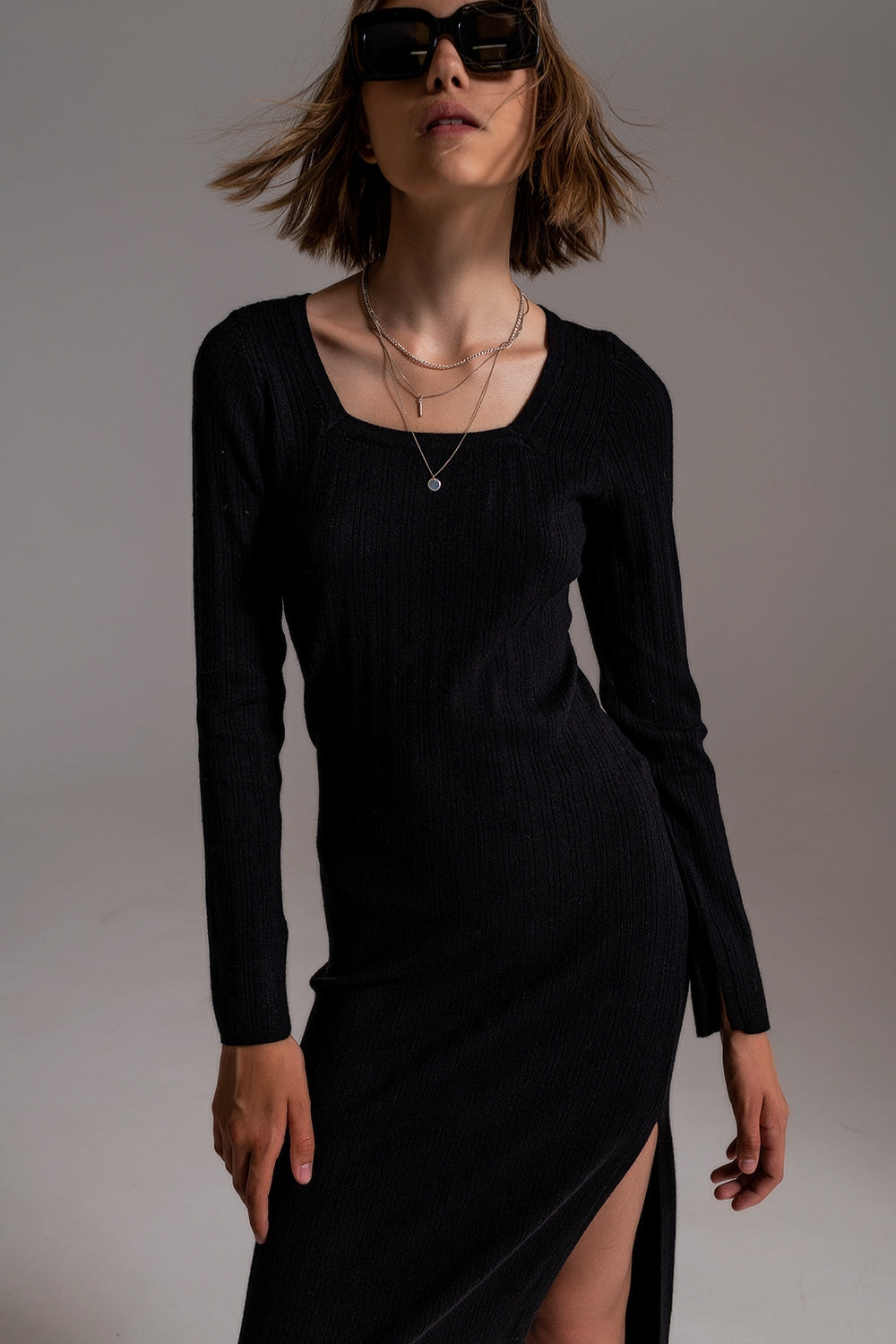 vestido midi de punto ajustado en color negro, de manga larga y con escote cuadrado.