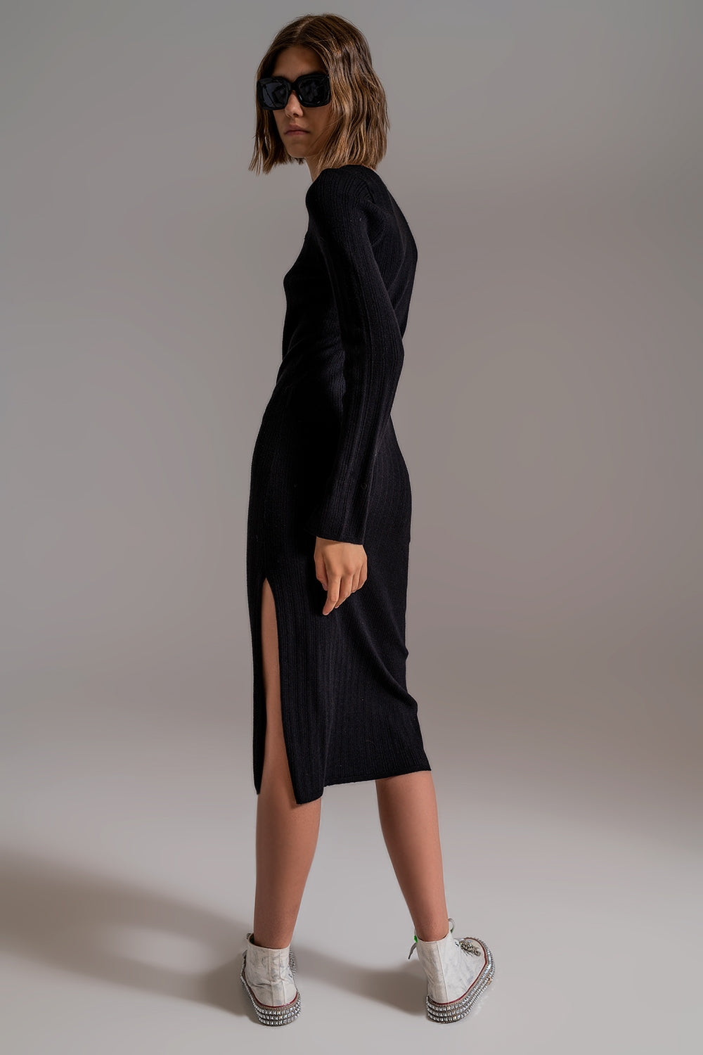 Vista de perfil de un vestido midi de punto negro ajustado.