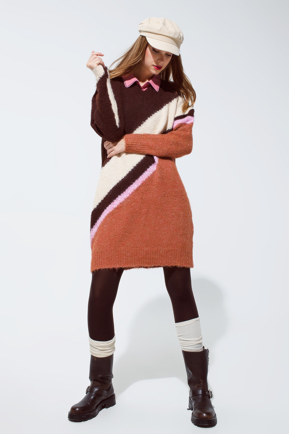 Modelo con look completo de vestido-jersey de punto grueso estilo años 70, camisa, gorra y botas.