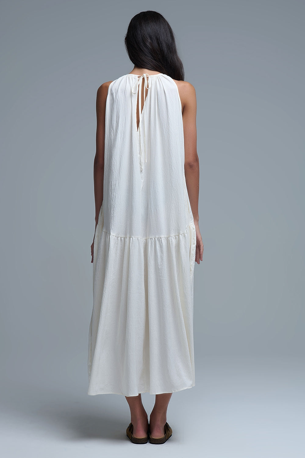 Vestido largo de color blanco roto con cuello halter y silueta maxi muy holgada, tejido texturizado con bolsillos laterales ocultos y collar étnico.