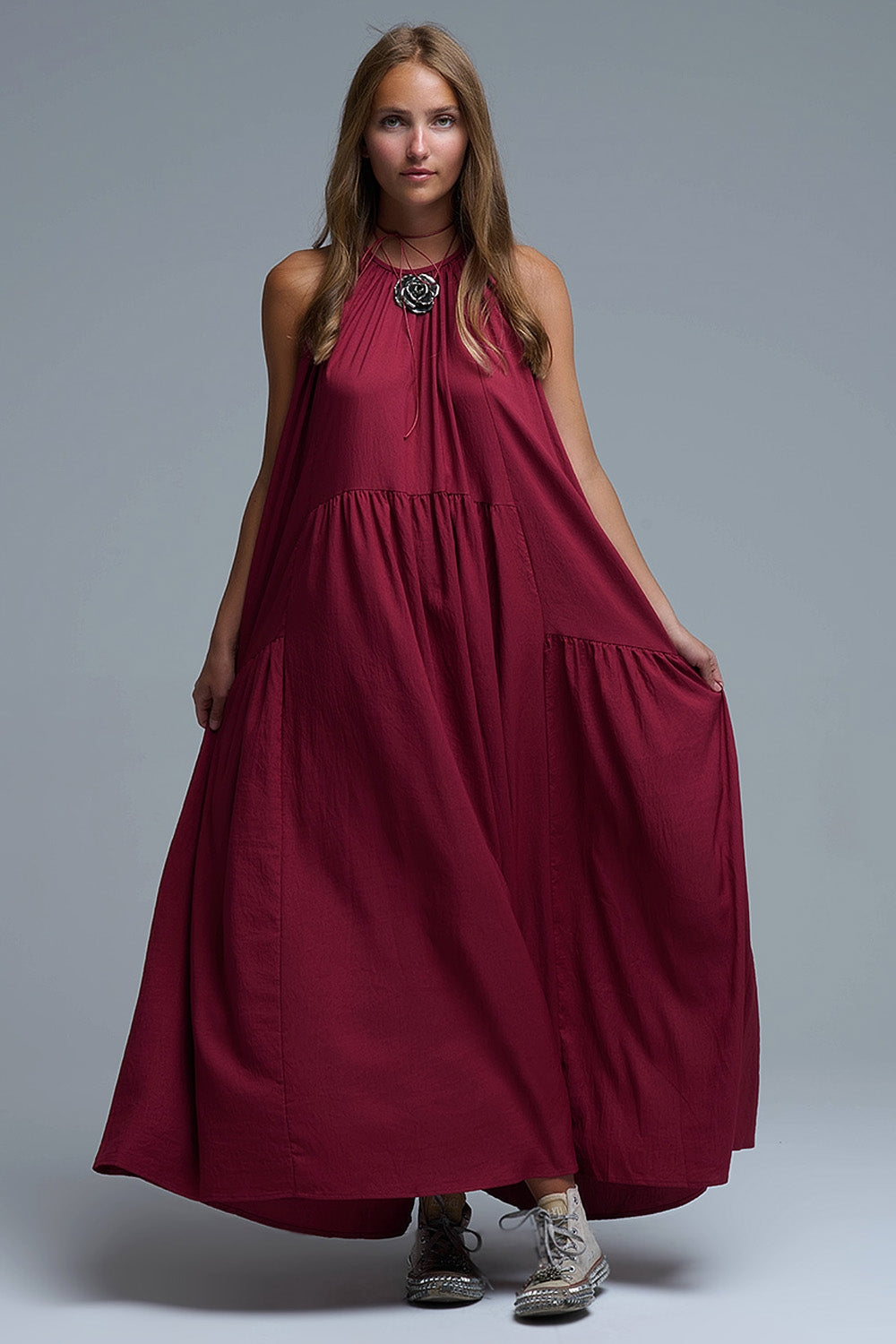 Vestido largo de color burdeos con cuello halter y silueta maxi muy holgada, paneles fruncidos con caída fluida y bolsillos laterales ocultos.