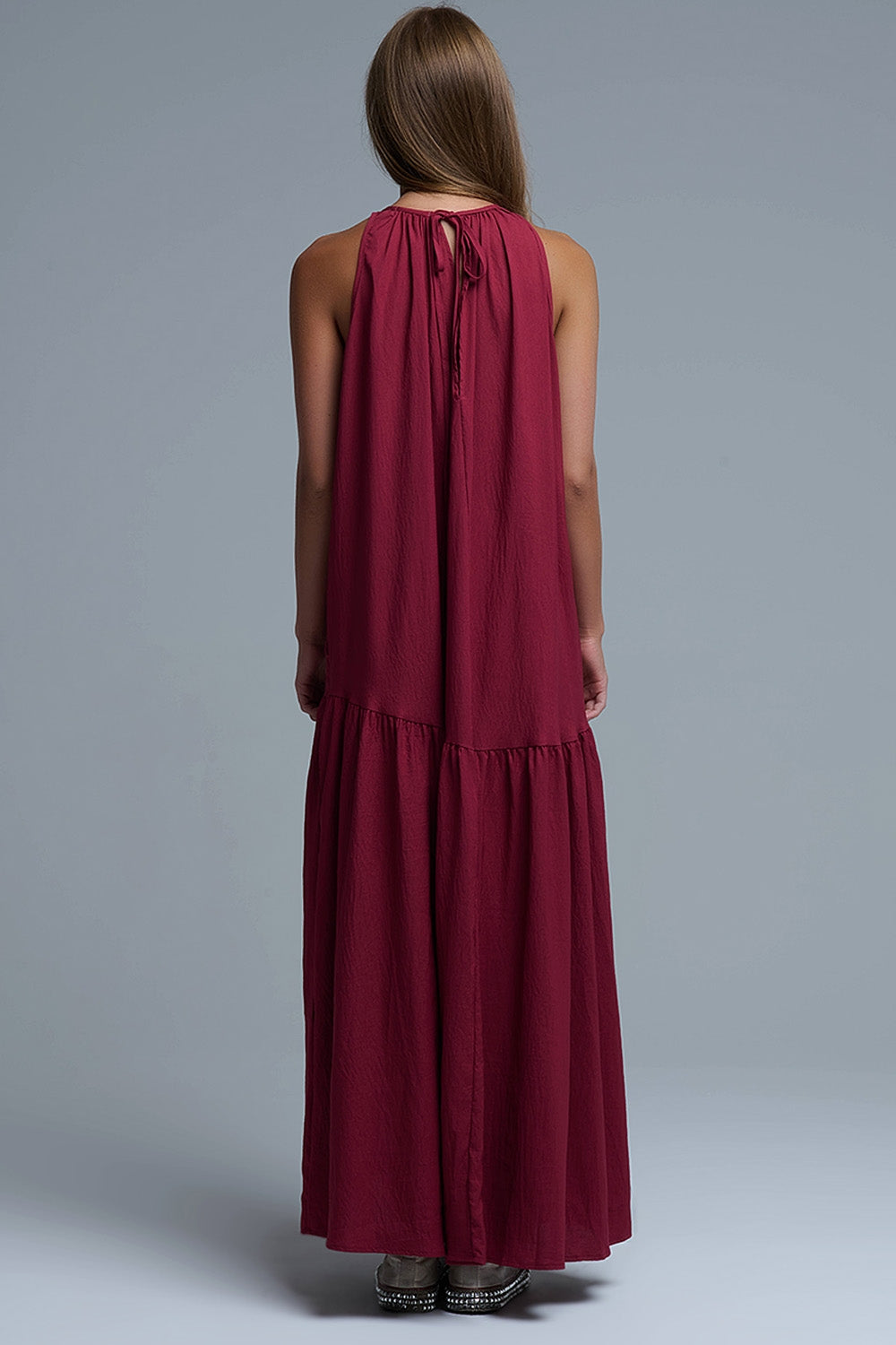Vista trasera de vestido maxi burdeos con escote halter, espalda descubierta profunda y detalle de lazo ajustable en el cuello.