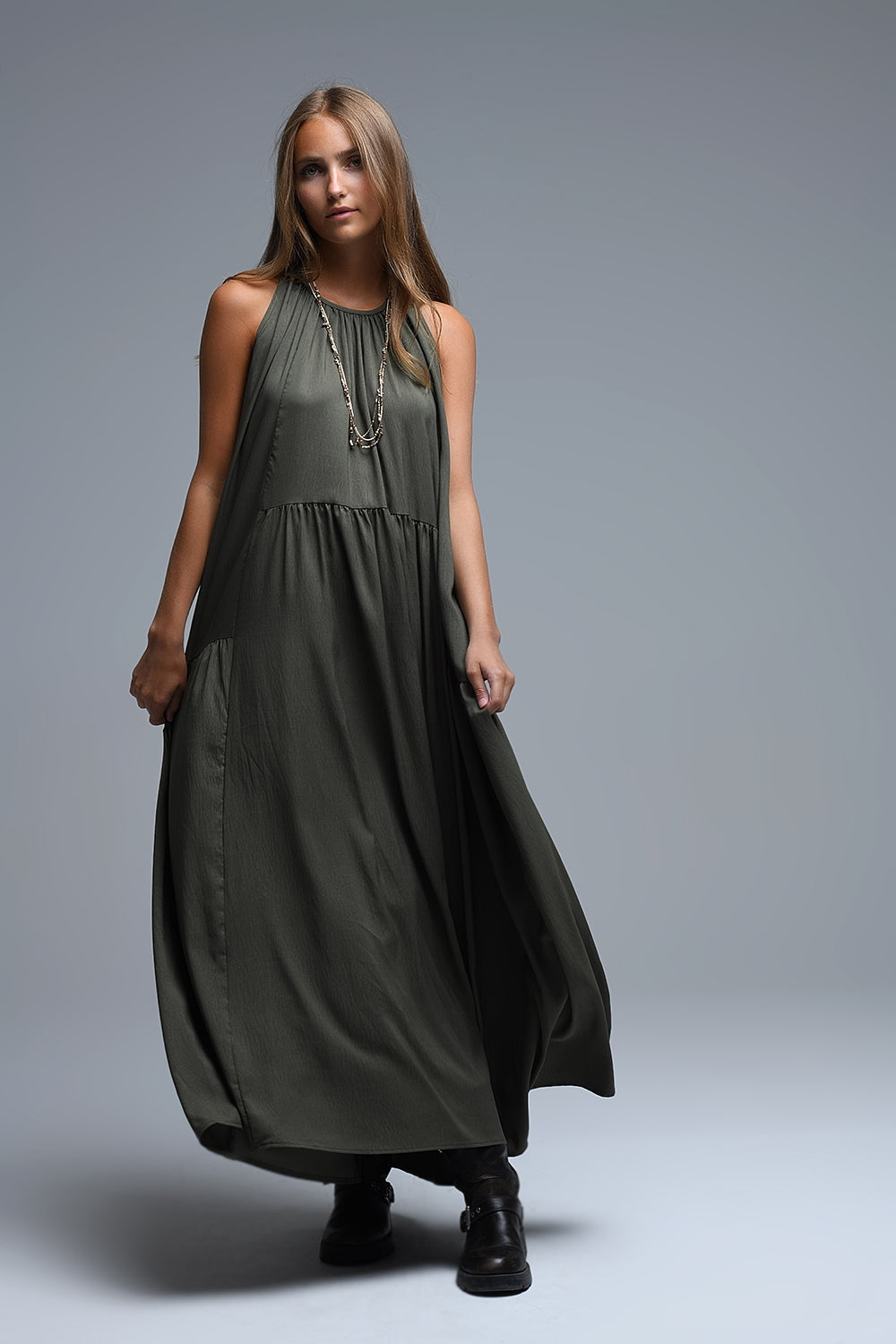 Vestido largo de color verde caqui con cuello halter y silueta maxi muy holgada, paneles fruncidos fluidos y bolsillos laterales ocultos.