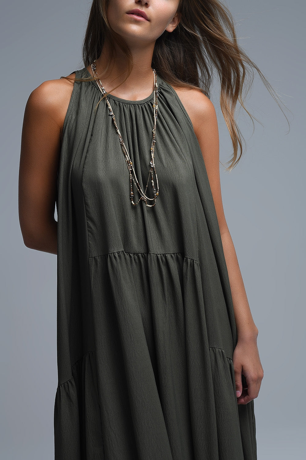 Vestido largo de color verde caqui con cuello halter y silueta maxi muy holgada, paneles fruncidos fluidos y bolsillos laterales ocultos.